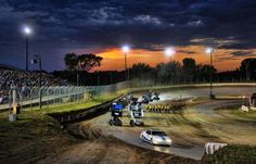 a dirt track with cars driving on it at night