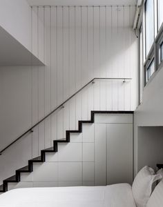 a bed sitting under a stair case next to a window