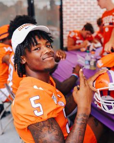 a man in an orange football uniform sitting at a table with other people around him