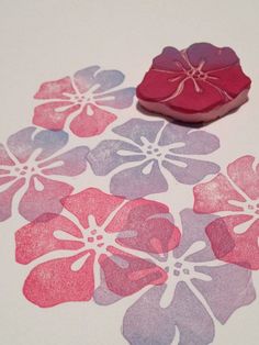 some pink and purple flowers are next to a wax stamp on a white table top