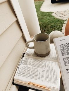 an open book and coffee cup sitting on a table outside with the pages spread out