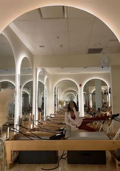 a woman is sitting on a bench in a room with many mirrors and lights around her