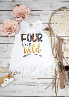 a white shirt with the words four ever wild printed on it next to some flowers