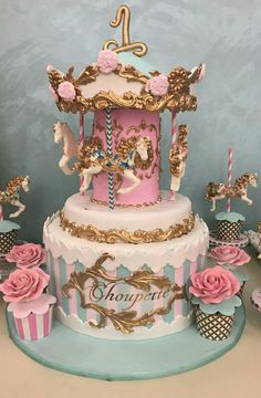 a pink and gold carousel cake surrounded by cupcakes, roses and other decorations