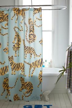 a bathroom with a shower curtain that has tiger designs on it and blue letters in front of the shower