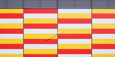 a red, yellow and white striped wall next to a building