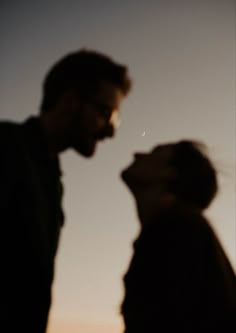 two people standing next to each other with the moon in the sky behind them,