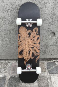 a skateboard with an octopus on it is leaning up against a wall and has white wheels