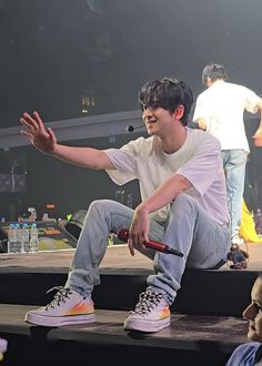 a young man sitting on top of a stage with his hands out to the side