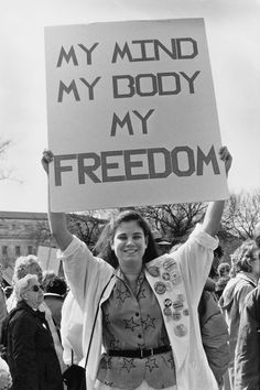 a woman holding up a sign that says my mind my body my freedom