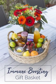 a basket filled with fruit and flowers sitting on top of a table next to an orange juice