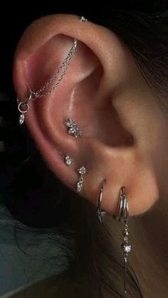 a woman's ear with three different piercings