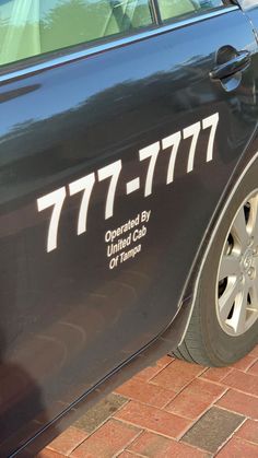 a black car with hebrew writing on it parked in front of a brick sidewalk next to a building