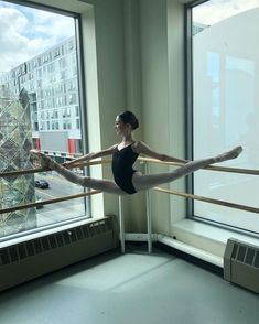 a woman in black leotard and ballet shoes standing on one leg while holding a pole