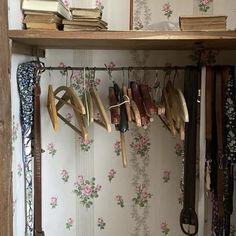 an open book shelf filled with lots of different types of shoes and ties hanging from hooks