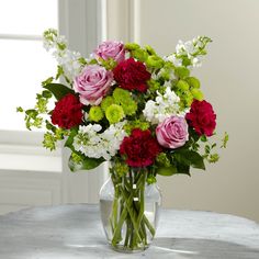 a vase filled with red, white and green flowers