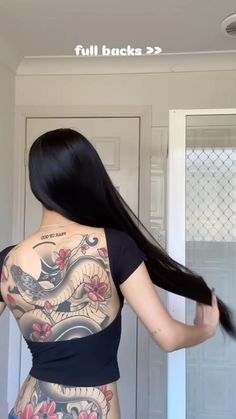 a woman with tattoos on her back standing in front of a door