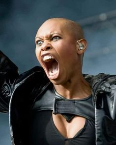 a woman with an open mouth and piercings on her head, wearing black leather clothes