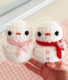 two crocheted snowmen with red scarfs on their heads, one is holding the other