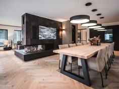 a modern dining room with wood flooring and large tv mounted on the wall above the fireplace