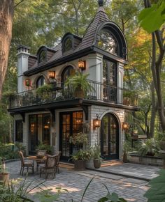 a large house with lots of windows and plants on the front porch, surrounded by greenery