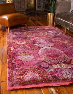 a large pink rug in a living room next to a brown leather chair and couch