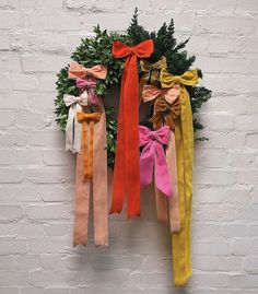 a wreath with ribbons hanging on the side of a wall next to a brick wall