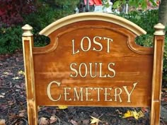 a wooden sign that says lost souls cemetery in front of some trees and leaves