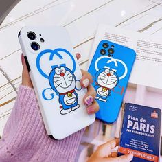 a person holding two cell phones with cartoon characters on them, one is blue and the other is white