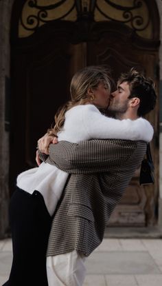 a man and woman embracing each other in front of a building