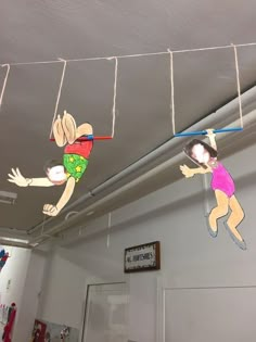 two children's paper cutouts hanging from the ceiling in an office building,