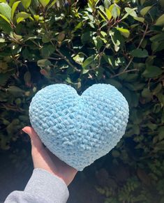 a hand holding a blue heart shaped pillow