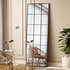 a mirror sitting on top of a wooden floor next to a chair and potted plant