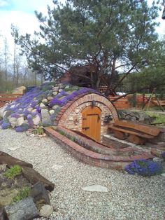 an outdoor area with benches and a stone fire pit in the middle, surrounded by lavender flowers