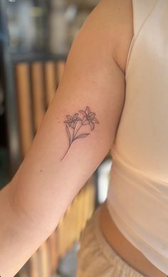 a woman's arm with a small flower tattoo on the left side of her arm