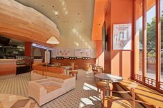 the inside of a restaurant with orange walls and wooden tables, chairs, and benches