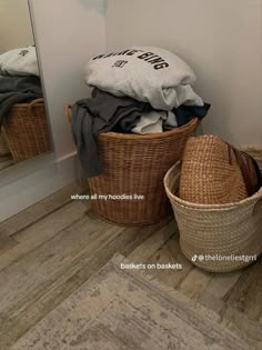 some baskets are sitting on the floor in front of a mirror and another basket is next to it