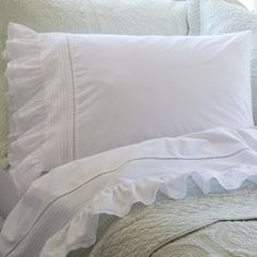 a bed with white sheets and pillows on it