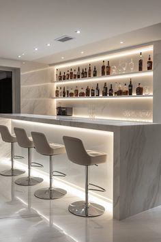 a bar with stools and bottles on the wall behind it in a white room