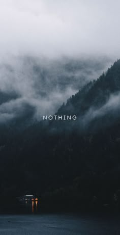 the words nothing are written in front of a mountain range with fog and low lying clouds