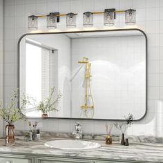 a bathroom sink with a large mirror above it and vases on the counter next to it