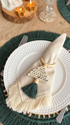 a white plate topped with a napkin and a green tasseled decoration on top of it