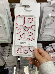 someone holding up a cell phone case with hearts on it in a store display area