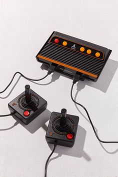 two old school video game controllers hooked up to each other on a white table top