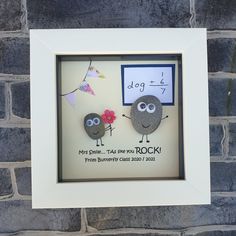 two rocks in a frame with the words dog and rock written on them, hanging from a brick wall