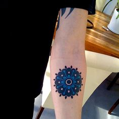 a person with a tattoo on their arm has a blue and white flower in the center