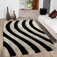 a black and white rug in a living room next to a couch with two vases on the floor