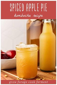 two jars filled with liquid sitting on top of a wooden table next to an apple