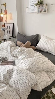 an unmade bed with white and grey striped sheets