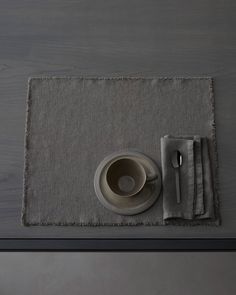 a place mat with a cup and saucer on it next to a fork and spoon